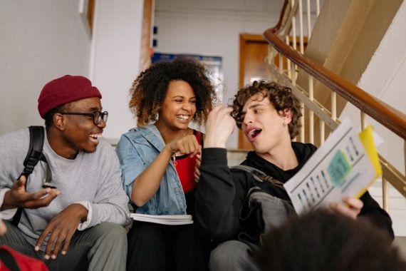 Three teenagers laughing together on school steps after dismissal